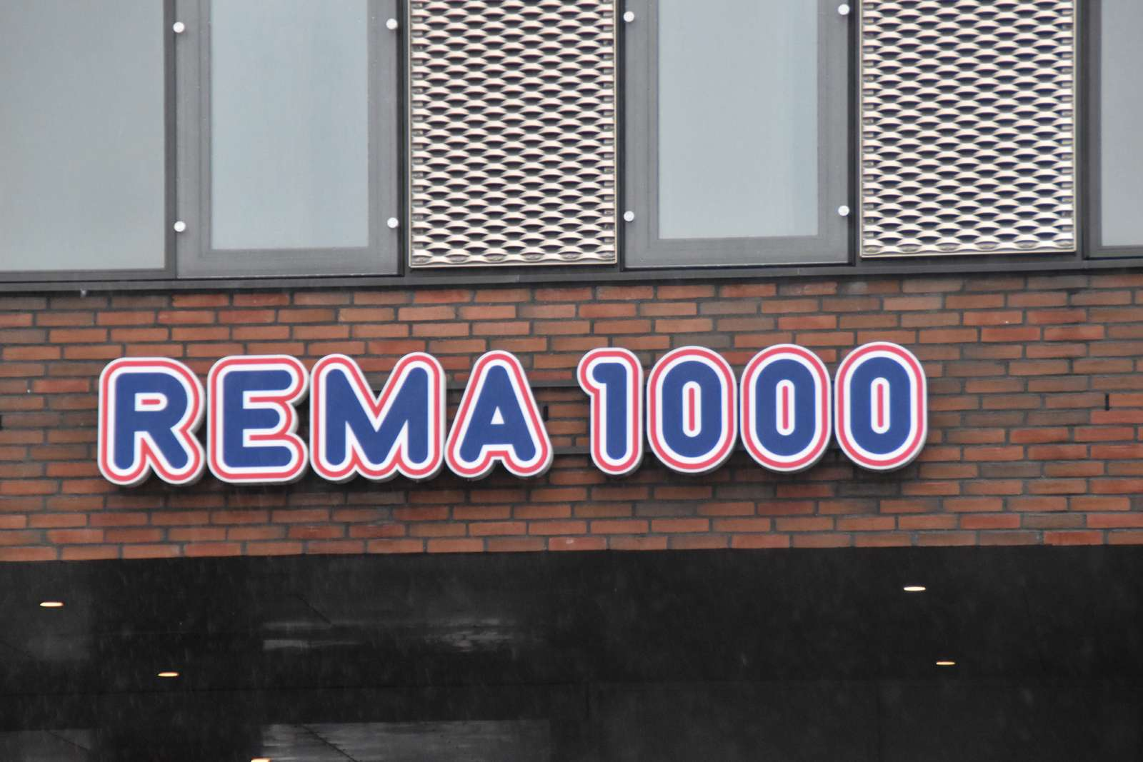 Det her er et billede af Rema 1000s logo. Fronten på en butik.