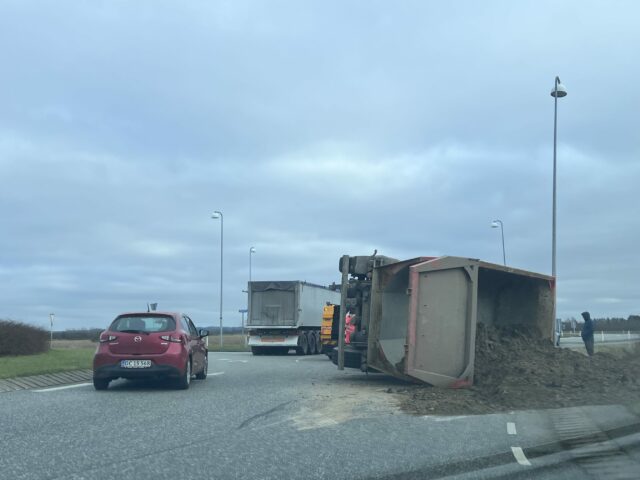 Lastbil læsset med jord vælter i rundkørsel