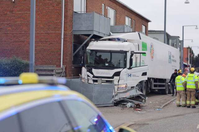 Lastbil torpederer lyskryds og parkerede biler: Sidder fast i altan