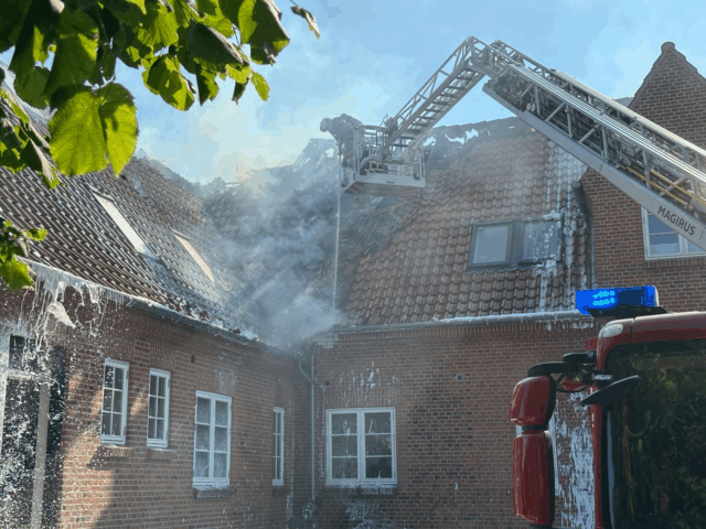Røg vælter ud af taget på bygning