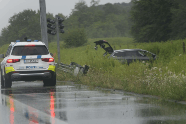 Bil ender uden for autoværnet i regnvådt uheld