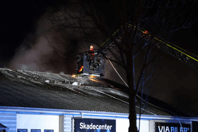Kraftig brand i værksted: Flammerne slår op gennem taget – droner i luften