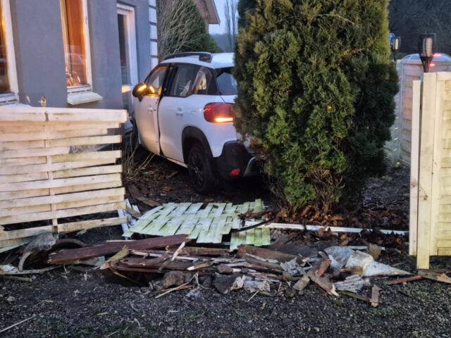 Bil brager gennem hegn og ind i husmur